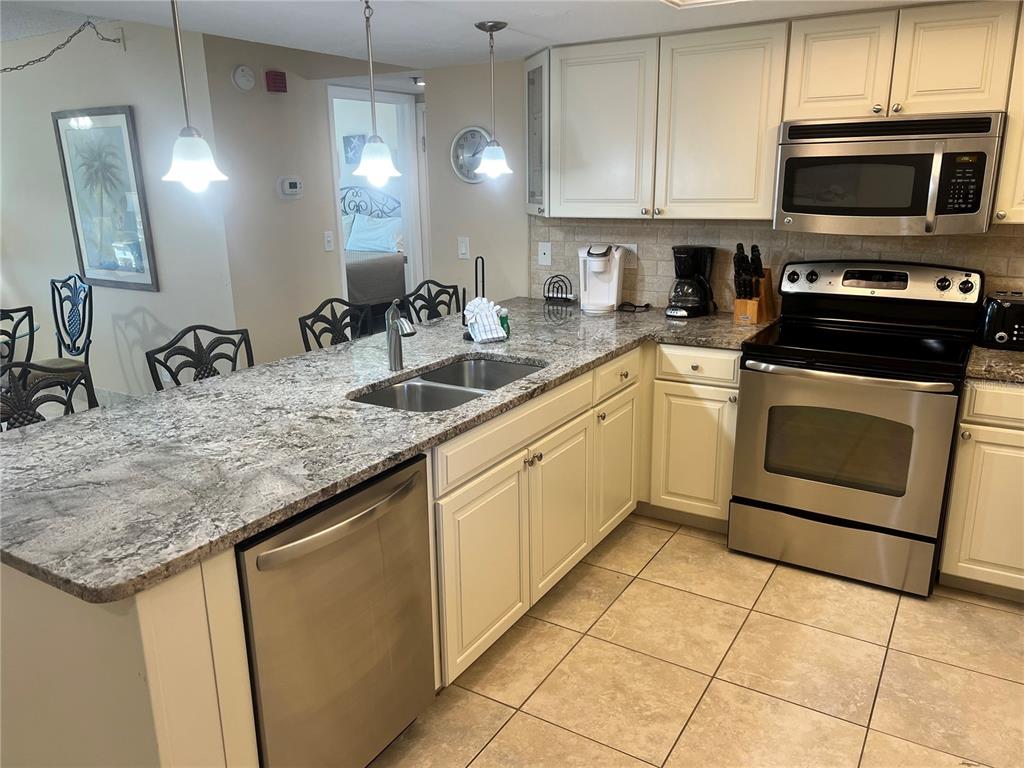 A kitchen features granite countertops, stainless steel appliances, and white cabinets over tile flooring — 1001 POINT OF ROCKS ROAD UNIT 310, SARASOTA, FL