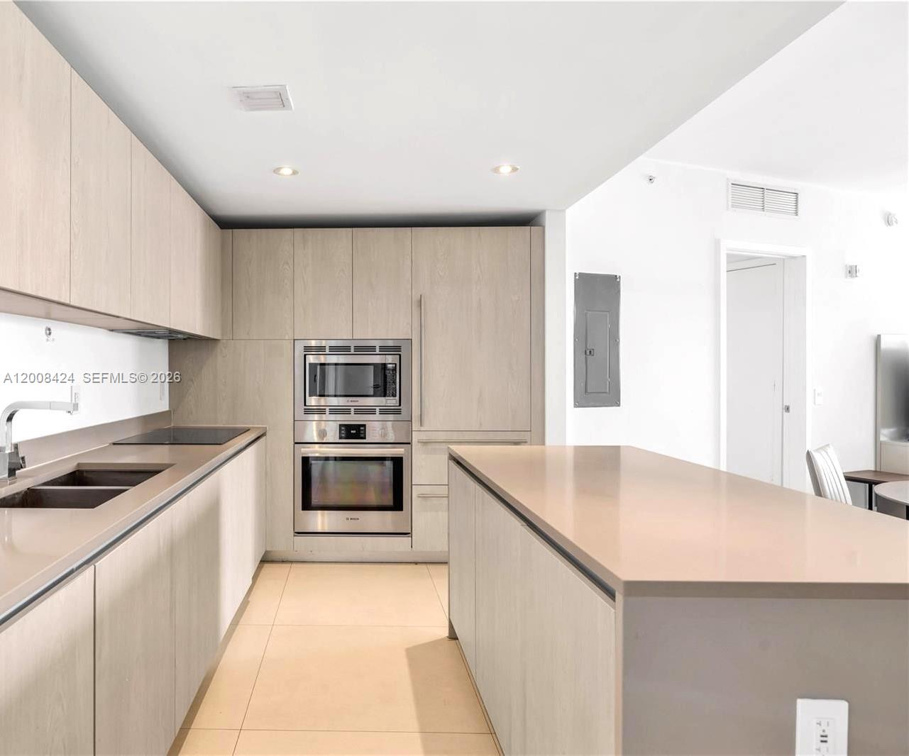 A modern kitchen features light wood cabinetry, stainless steel appliances, and a large central island — 4111 S Ocean Dr # 2303, Hollywood FL 33019, HOLLYWOOD, FL