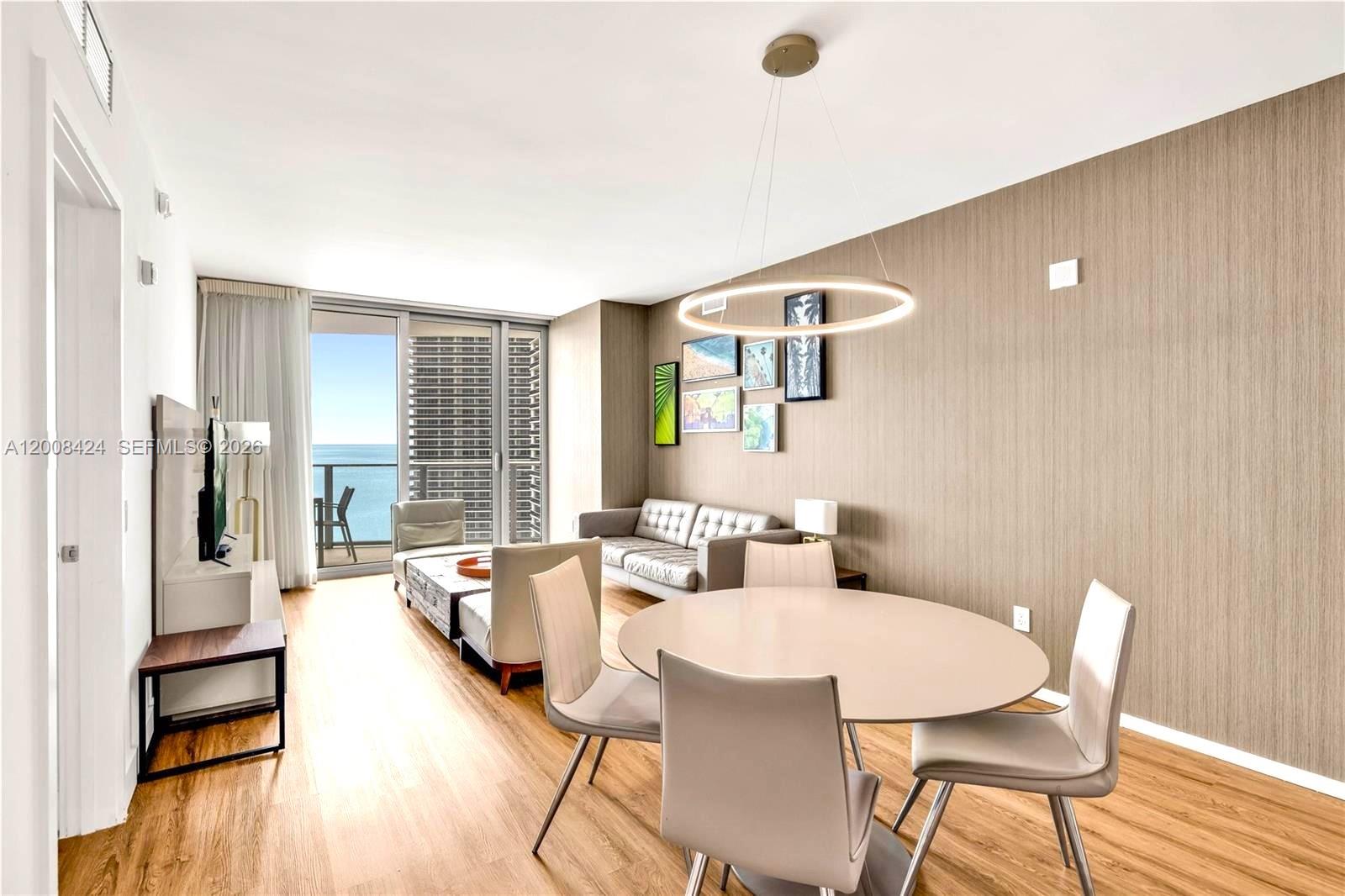 A living and dining area features a round table, modern furniture, and a balcony view — 4111 S Ocean Dr # 2303, Hollywood FL 33019, HOLLYWOOD, FL