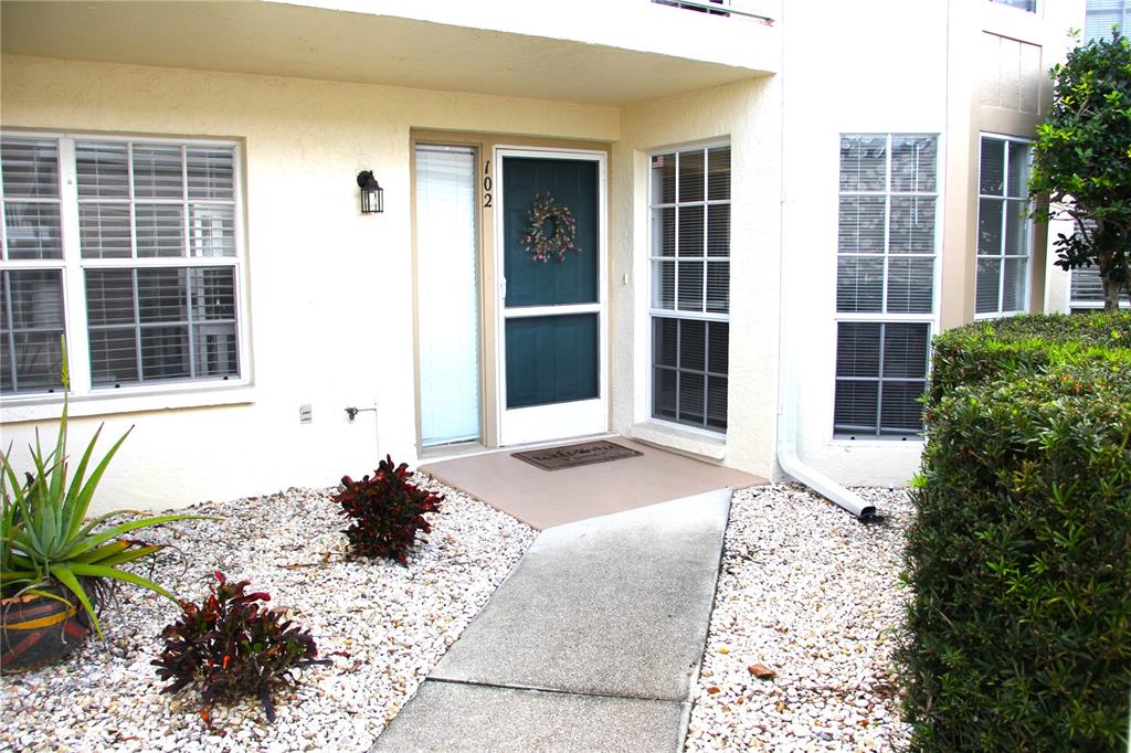 A beige exterior features a front door with a wreath, a walkway, and gravel landscaping — 204 SILVER LAKE DRIVE UNIT 102, VENICE, FL