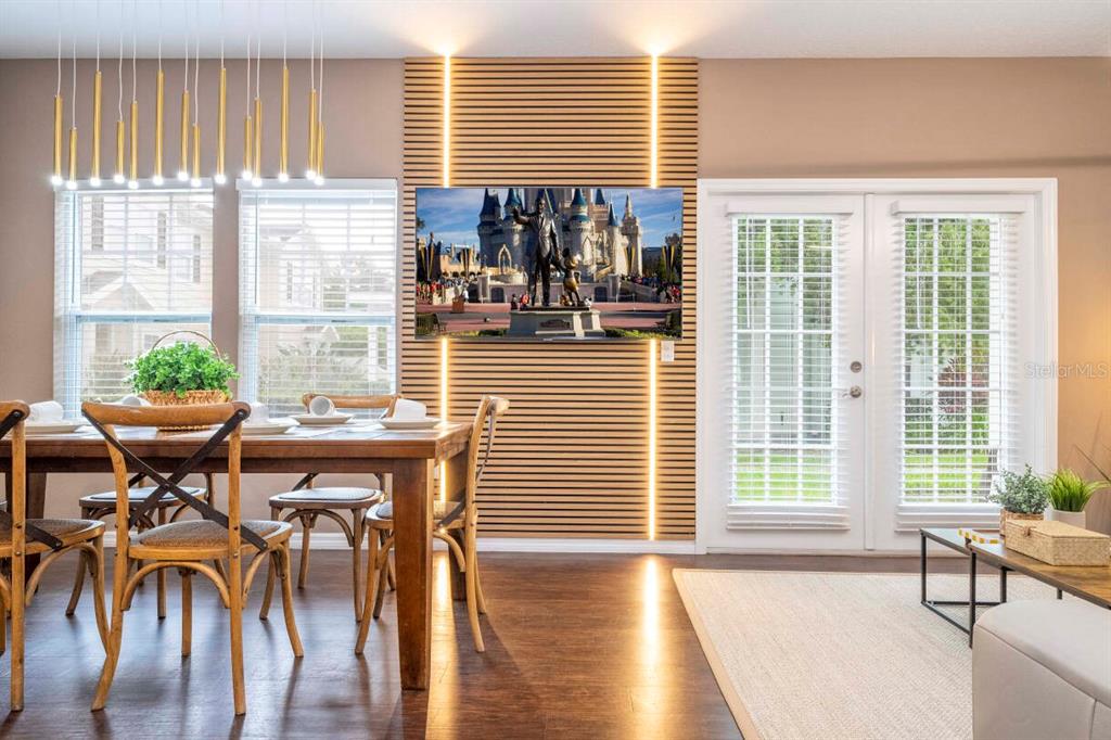 A dining area features a wood-slat accent wall with integrated lighting and a wall-mounted television — 2901 EDENSHIRE WAY UNIT 104, KISSIMMEE, FL