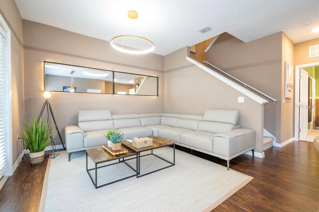 A living room features a light gray sectional sofa, two coffee tables, and a wall mirror — 2901 EDENSHIRE WAY UNIT 104, KISSIMMEE, FL