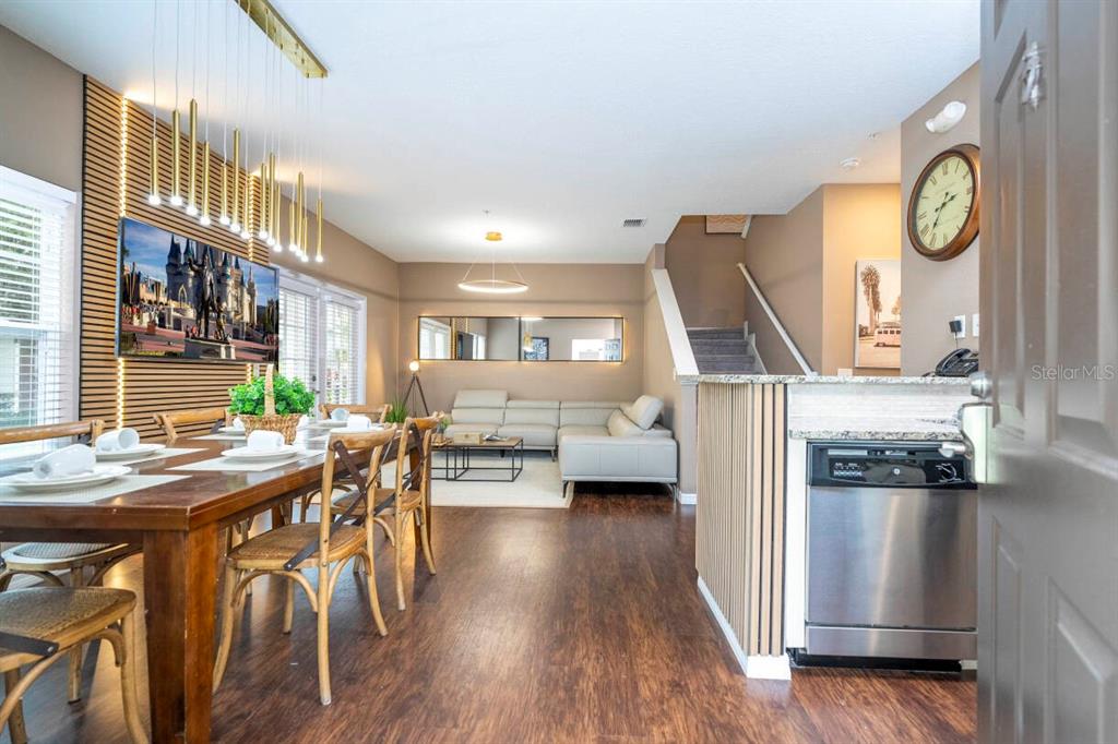 A dining area and living room feature wood-look flooring, a slat wall, and a staircase — 2901 EDENSHIRE WAY UNIT 104, KISSIMMEE, FL