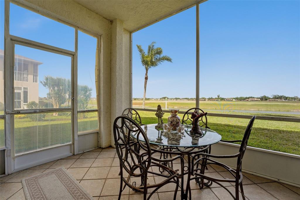 A screened-in patio features a glass-topped table, metal chairs, and a view of a lake — 5800 SABAL TRACE DRIVE UNIT 401, NORTH PORT, FL
