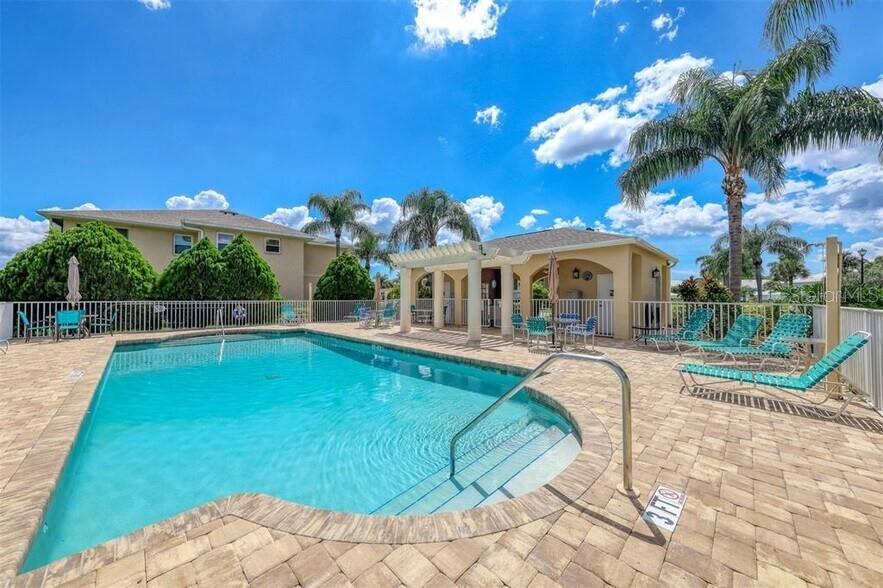 A swimming pool with a pergola and lounge chairs sits on a paved patio — 5800 SABAL TRACE DRIVE UNIT 401, NORTH PORT, FL