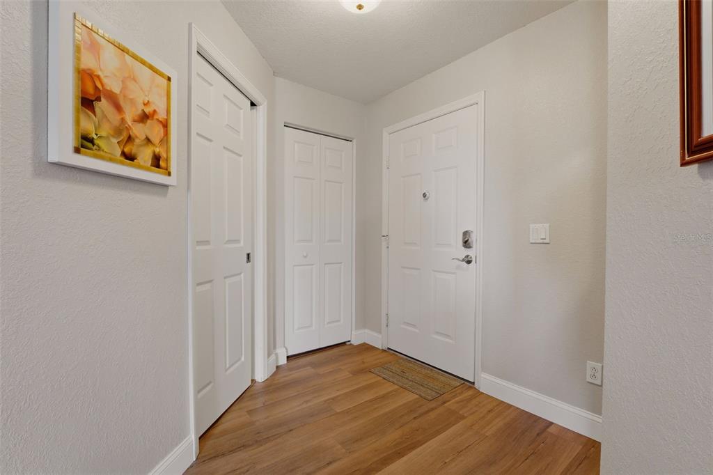 An entryway features wood-look flooring, white walls, two closet doors, and a front door — 5800 SABAL TRACE DRIVE UNIT 401, NORTH PORT, FL