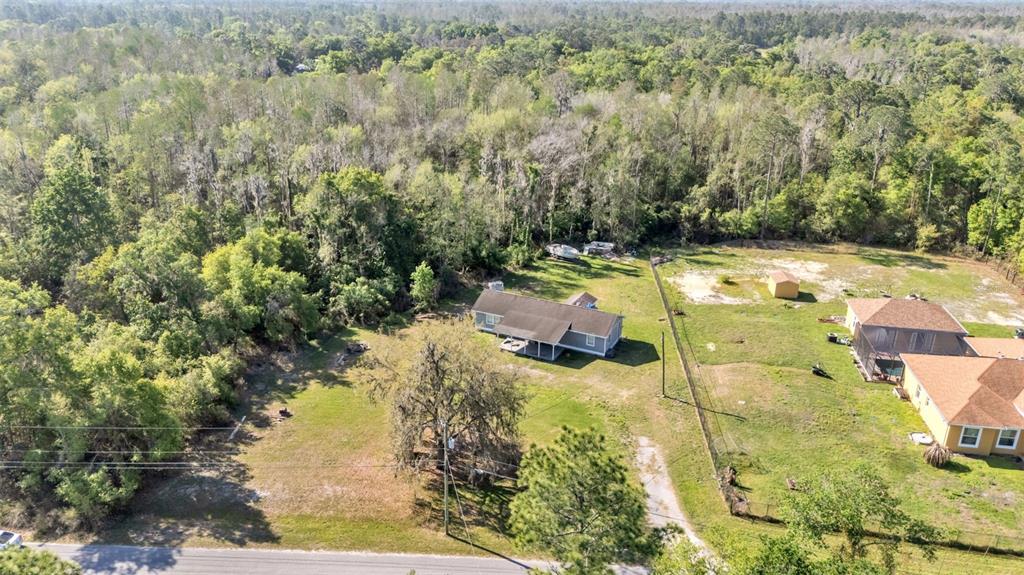 An aerial view shows two houses on large, grassy lots bordered by a dense forest — 342 CREEKWOOD RUN, LAKELAND, FL