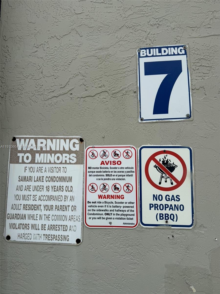 A wall displays a building number sign, a warning for minors, a vehicle restriction, and a barbecue prohibition — 10090 NW 80th Ct # 1206, Hialeah Gardens FL 33016, HIALEAH GARDENS, FL