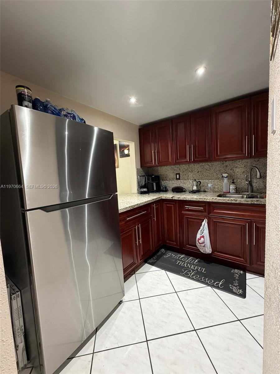 A kitchen features stainless steel appliances, dark wood cabinets, granite countertops, and white tiled floors — 10090 NW 80th Ct # 1206, Hialeah Gardens FL 33016, HIALEAH GARDENS, FL