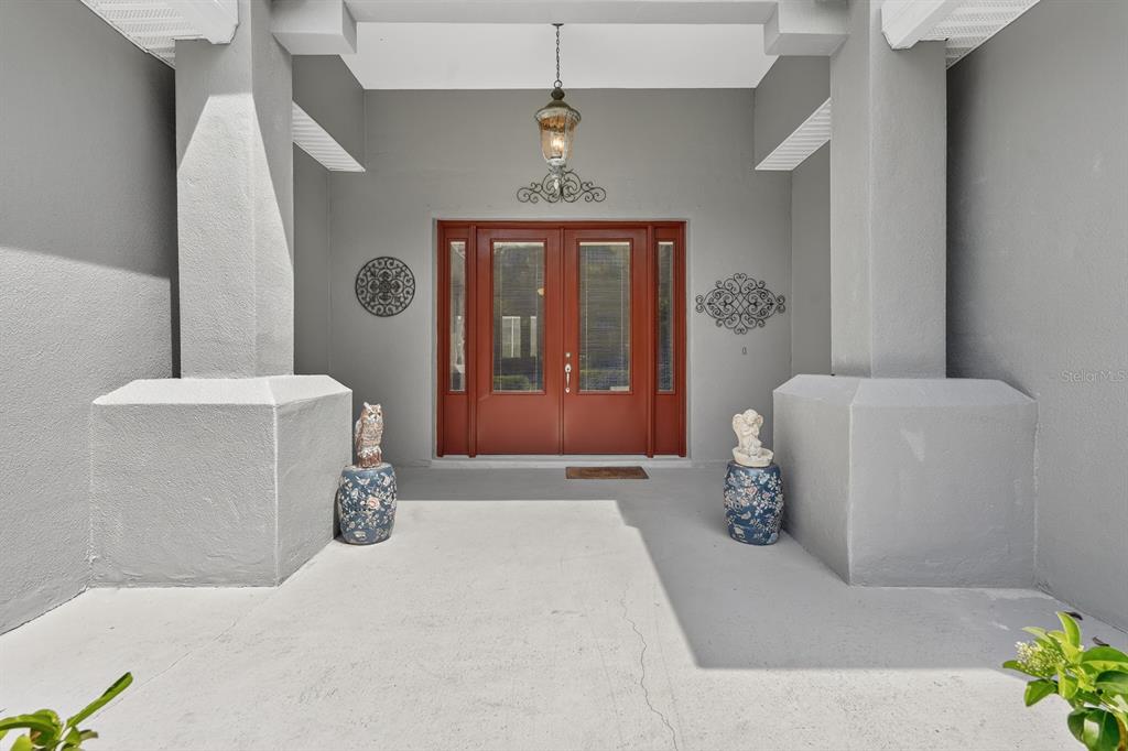 A covered entryway features a red double door, two decorative stools, and gray columns — 50 FURNESS PLACE, PALM COAST, FL
