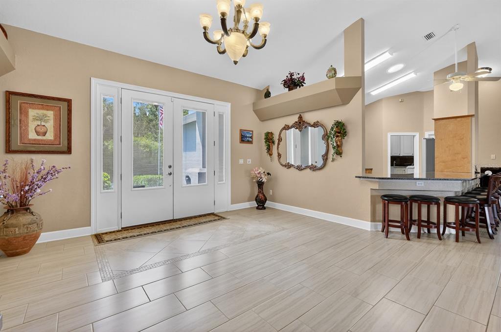 A bright entryway features light tile flooring, a double front door, and a breakfast bar — 50 FURNESS PLACE, PALM COAST, FL