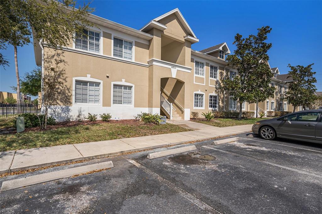 A multi-story apartment building exterior features tan stucco walls, white trim, and a central staircase — 6011 SKYDALE WAY UNIT 101, RIVERVIEW, FL