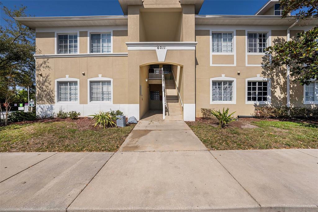 A two-story tan apartment building with a central staircase and a concrete walkway — 6011 SKYDALE WAY UNIT 101, RIVERVIEW, FL