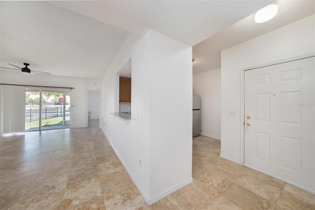 An interior view shows a tiled living area, a kitchen pass-through, and a white door — 6011 SKYDALE WAY UNIT 101, RIVERVIEW, FL