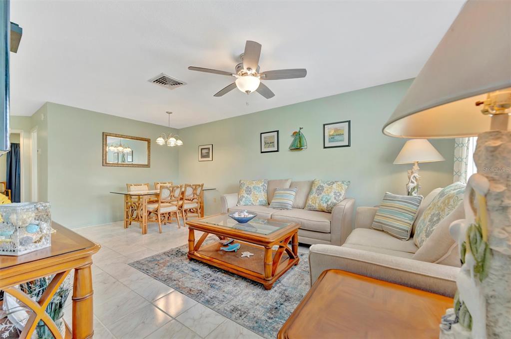 A kitchen features white cabinets, light countertops, a white stove, and a subway tile backsplash — 6057 CORAL WAY UNIT 3, BRADENTON, FL
