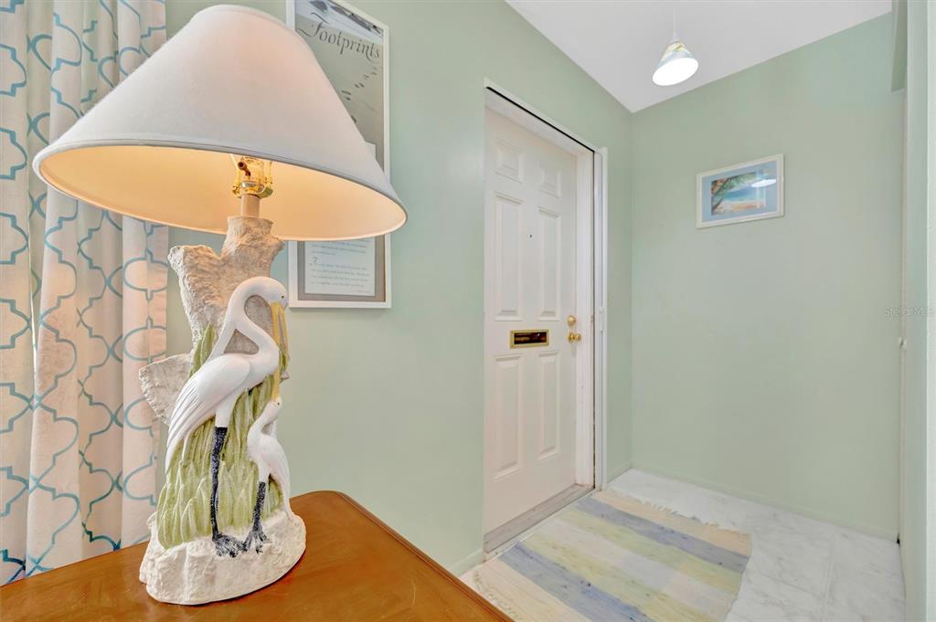 A living room and dining area with light green walls, tile floors, and coastal decor — 6057 CORAL WAY UNIT 3, BRADENTON, FL