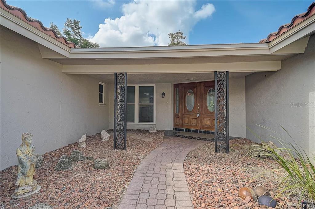 A paved walkway leads to a double-door entrance under a covered porch with decorative columns — 426 WHITFIELD AVENUE, SARASOTA, FL
