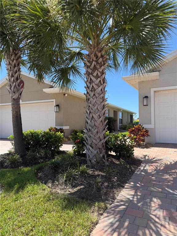 Two palm trees stand in front of two tan houses with white garage doors — 16058 BRIDLE RIDGE STREET, PORT CHARLOTTE, FL
