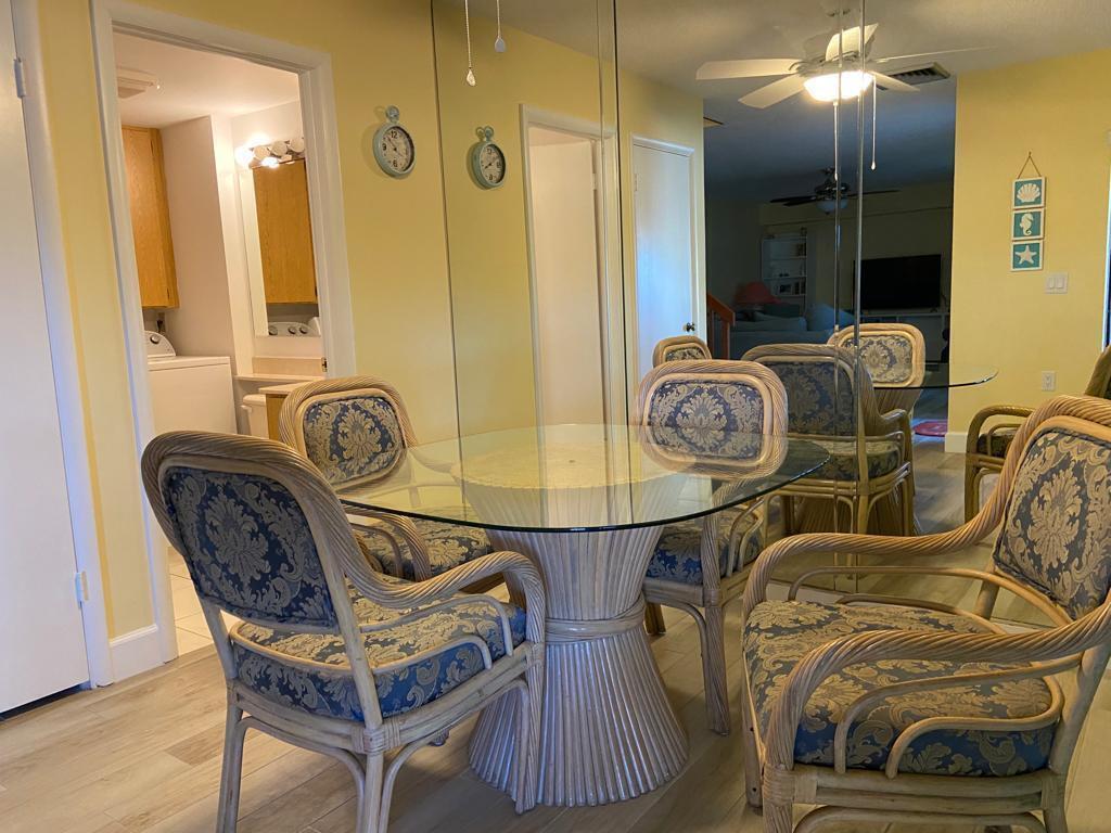 A dining area features a glass-topped rattan table with patterned chairs and mirrored walls — 8010 80th Way, West Palm Beach FL 33407, WEST PALM BEACH, FL