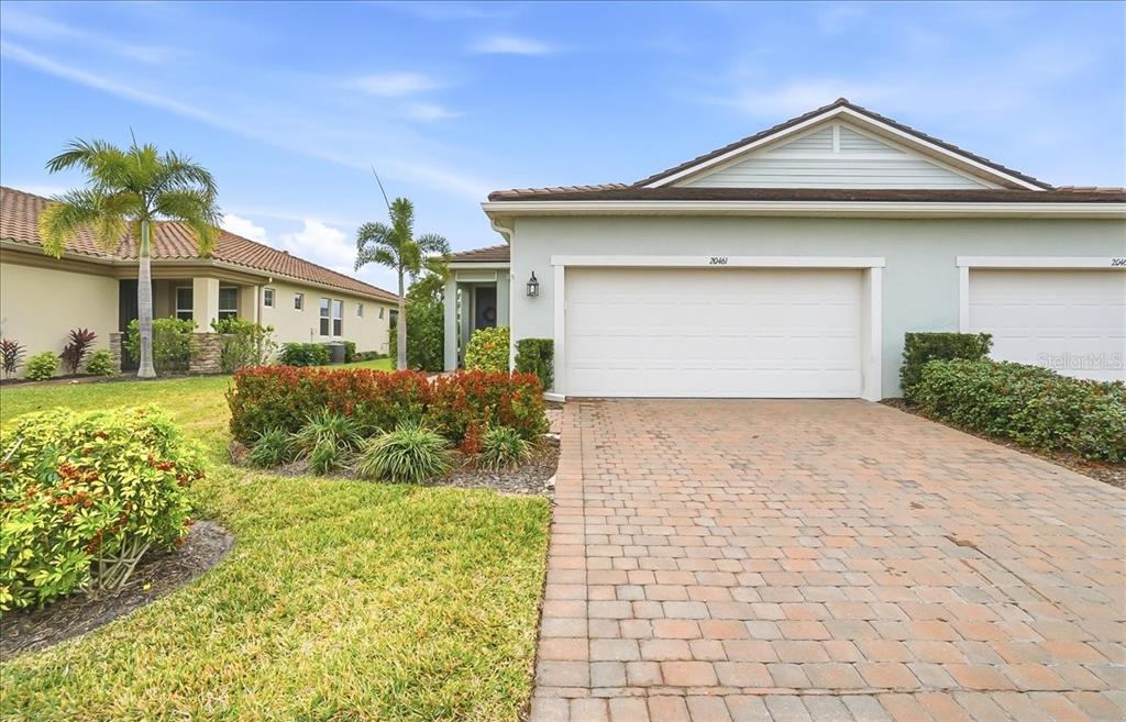 A light-colored single-story house features a two-car garage and a brick paver driveway — 20461 GALILEO PLACE, VENICE, FL