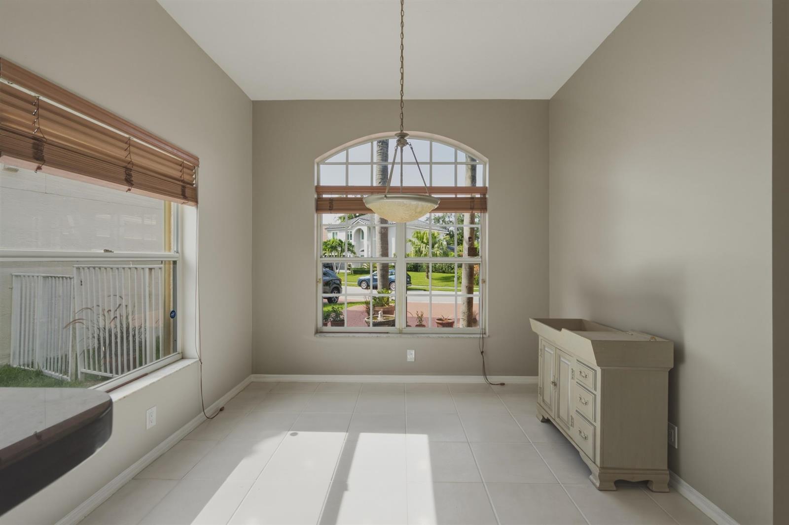 A dining area with tile floors, a large arched window, and a light-colored wooden cabinet — 10827 La Salinas Circle, Boca Raton FL 33428, BOCA RATON, FL