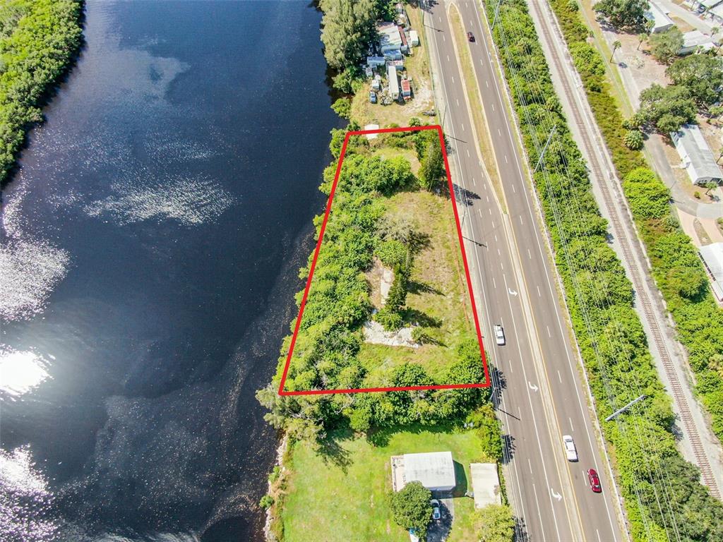 An aerial view shows a vacant, trapezoidal lot bordered by a river and a highway — 2508 S US HIGHWAY 41, RUSKIN, FL