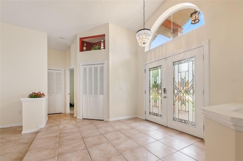 A bright foyer features tiled floors, a crystal chandelier, and double doors with decorative glass — 38 WESTMOUNT LANE, PALM COAST, FL