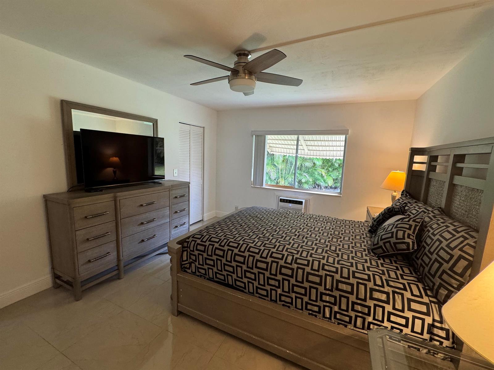 A bedroom features a wooden bed frame, matching dresser with mirror, and a ceiling fan — 5817 La Pinata Boulevard # 1, FL 33463, FL