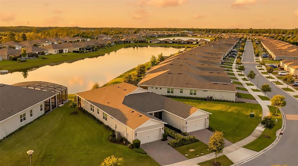 An aerial view shows a suburban neighborhood with houses surrounding a central retention pond — 2920 CHERRY BLOSSOM LOOP, ST CLOUD, FL