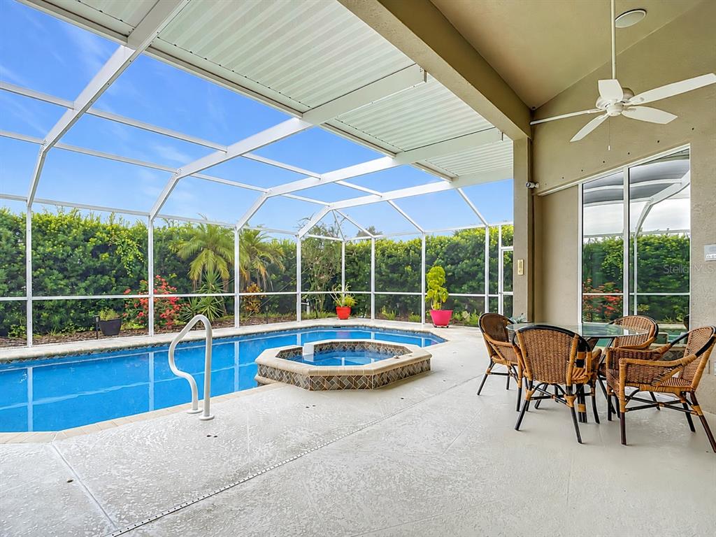A covered patio features a swimming pool with an integrated spa and outdoor dining furniture — 1736 NUREMBERG BOULEVARD, PUNTA GORDA, FL