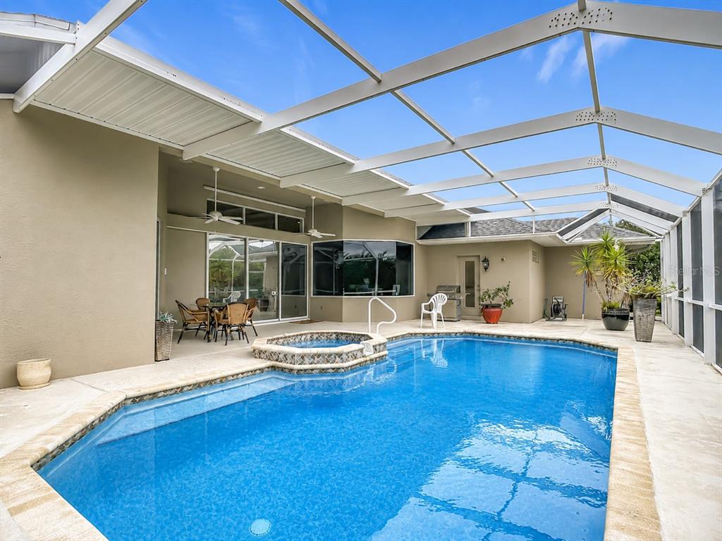 A screened-in patio features a swimming pool with an integrated hot tub and outdoor furniture — 1736 NUREMBERG BOULEVARD, PUNTA GORDA, FL