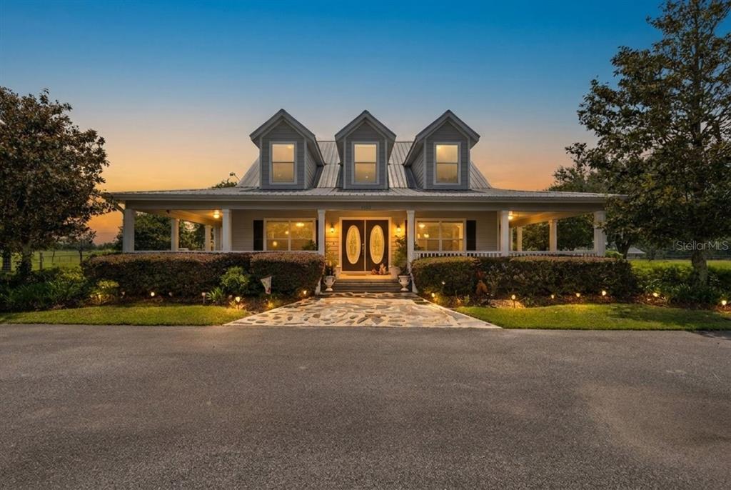 A single-story house with a wraparound porch and three dormer windows at sunset — 9897 NW 160 AVENUE, MORRISTON, FL