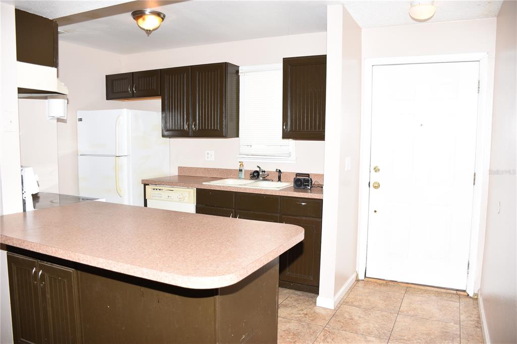 A kitchen features dark brown cabinets, a pink laminate countertop, and a white refrigerator — 1228 GOLCONDA ROAD, LAKELAND, FL