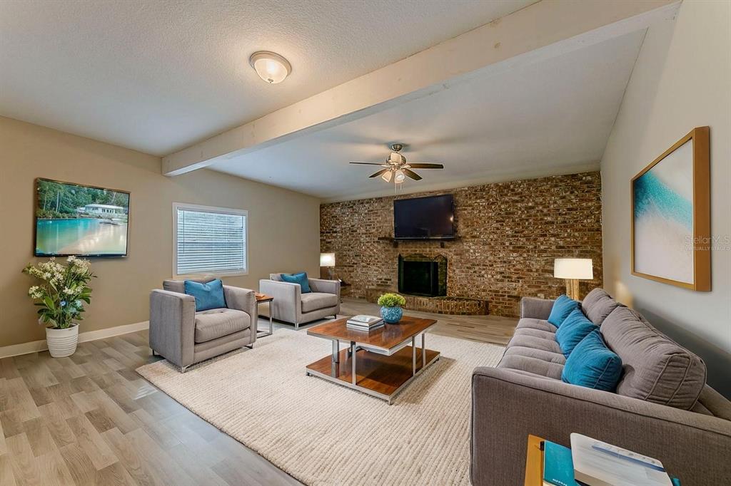 A living room features a brick fireplace, gray furniture, a wood coffee table, and wood-look flooring — 1007 EMERALDA ROAD, ORLANDO, FL