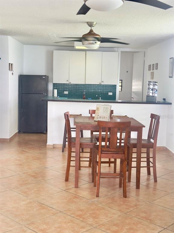 A kitchen with white cabinets and a dining area with a wooden table and chairs — Cond Villa. Marina 200 AVE. MARINA UNIT D-103, FAJARDO, PR