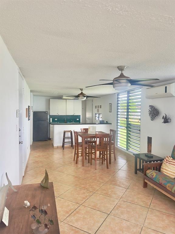 This open-concept living and dining area features tile flooring, a kitchen, and ceiling fans — Cond Villa. Marina 200 AVE. MARINA UNIT D-103, FAJARDO, PR