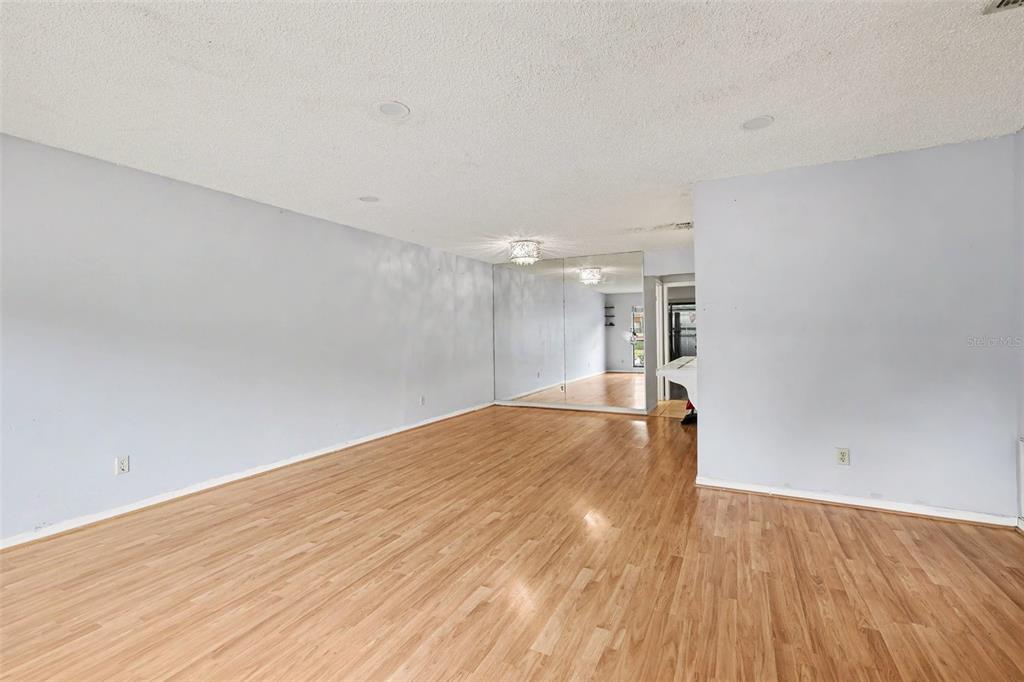 An empty room features light-colored walls, wood-look flooring, and a large mirrored wall section — 1916 SW 34TH COURT, OCALA, FL