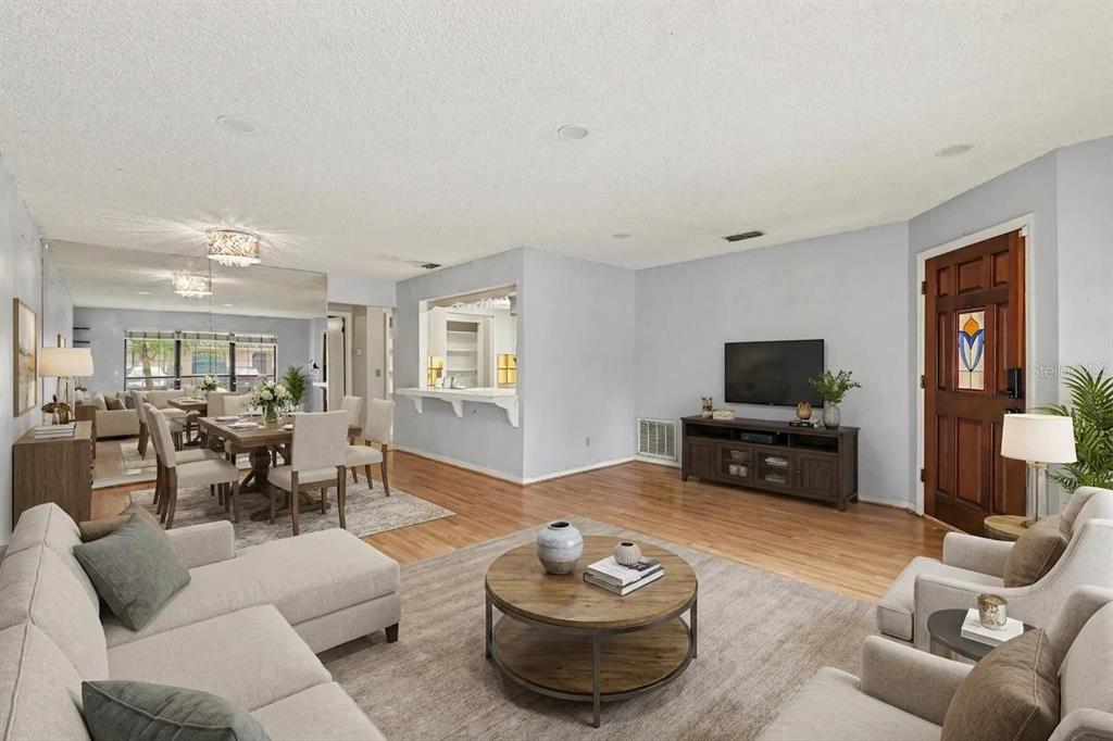 A living room and dining area with hardwood floors, a pass-through window, and mirrored walls — 1916 SW 34TH COURT, OCALA, FL