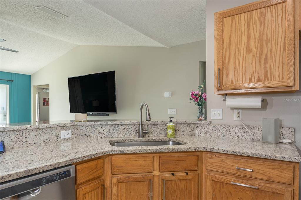 A kitchen sink with a granite countertop and oak cabinets in a home interior — 25 ROCKINGHAM LANE, PALM COAST, FL