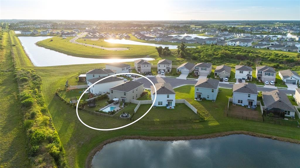 A backyard features a rectangular swimming pool, a patio with lounge furniture, and a sunset sky — 10016 BIG MARSH TERRACE, PARRISH, FL