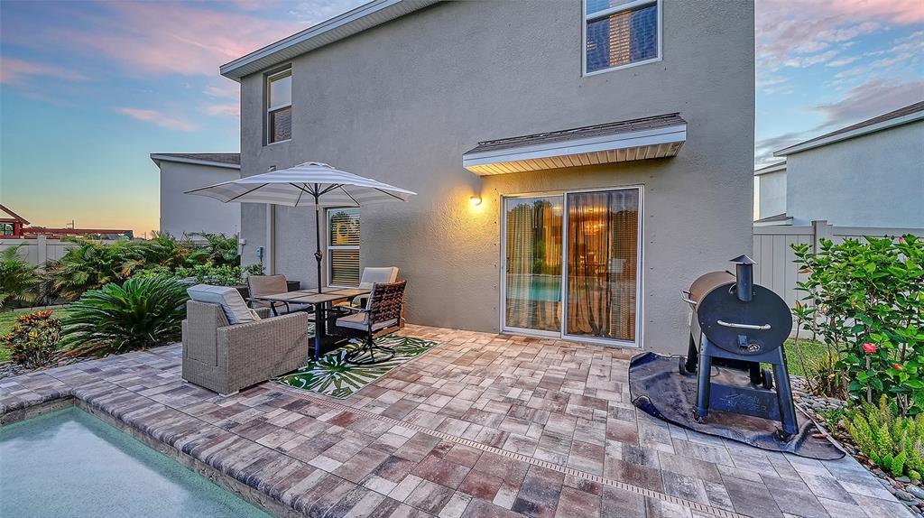 A backyard fire pit area with black chairs overlooks a pond and residential homes — 10016 BIG MARSH TERRACE, PARRISH, FL
