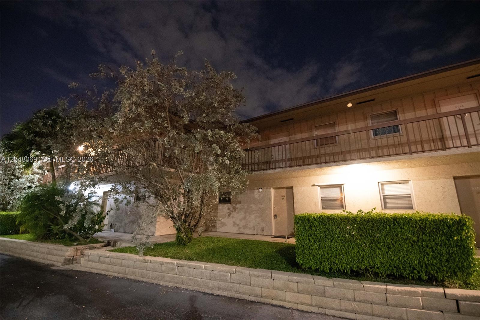 A two-story apartment building exterior features a balcony, landscaping, and a low stone wall — 2755 W Atlantic Ave # 105A, Delray Beach FL 33445, DELRAY BEACH, FL