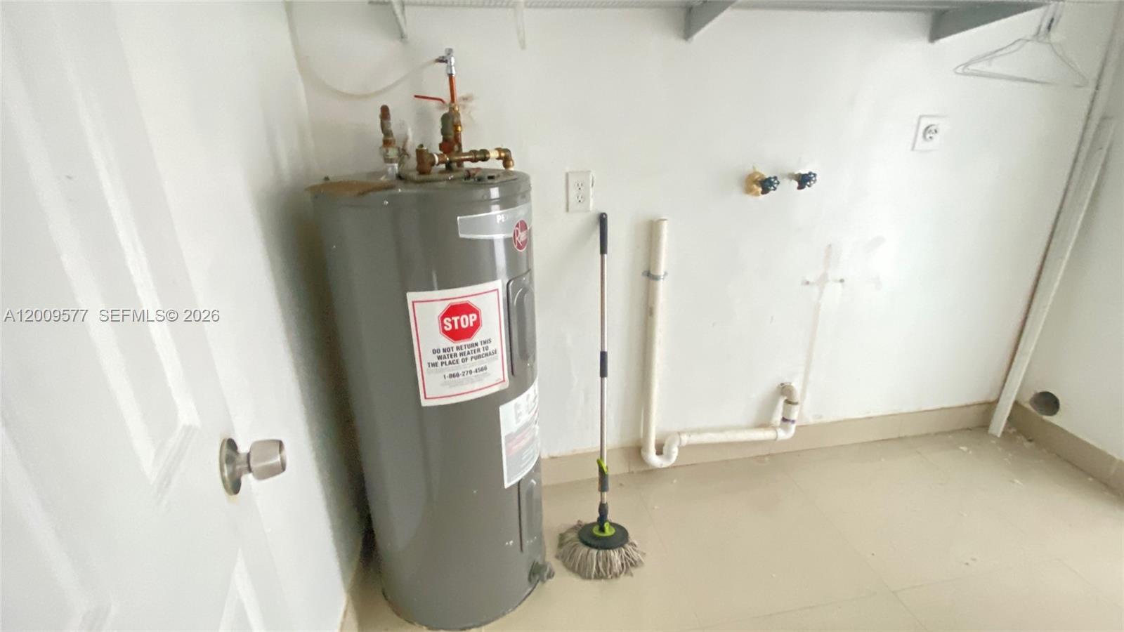 A water heater stands in a laundry room with plumbing connections on the wall — 530 NW 99th St, Miami FL 33150, MIAMI, FL