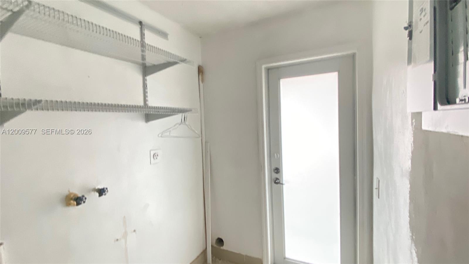 This laundry room features white walls, wire shelving, and a glass-paneled exterior door — 530 NW 99th St, Miami FL 33150, MIAMI, FL