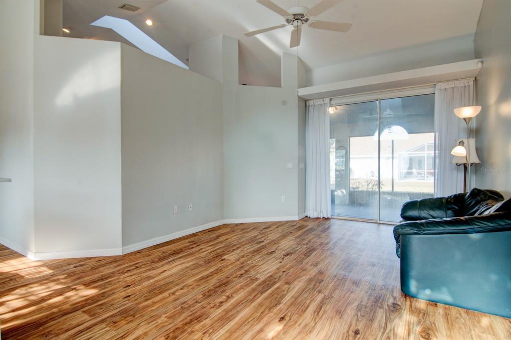 A living room features wood-look flooring, high ceilings, a ceiling fan, and sliding glass doors — 119 W FOREST OAK PLACE, BEVERLY HILLS, FL