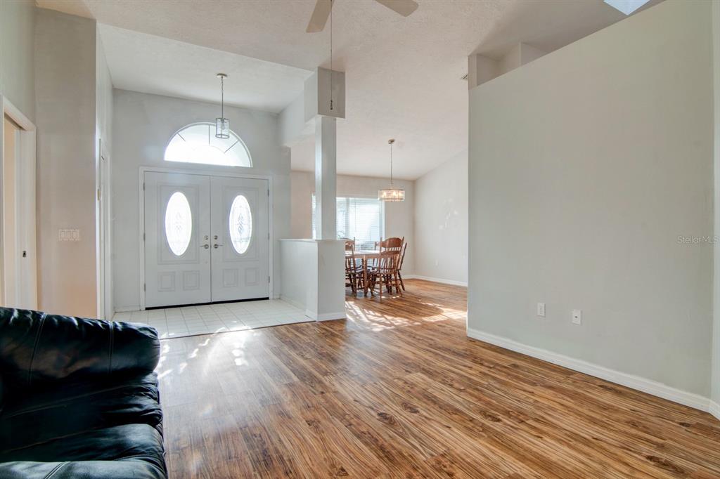 A living room with wood-look flooring leads to a dining area and a double-door entryway — 119 W FOREST OAK PLACE, BEVERLY HILLS, FL