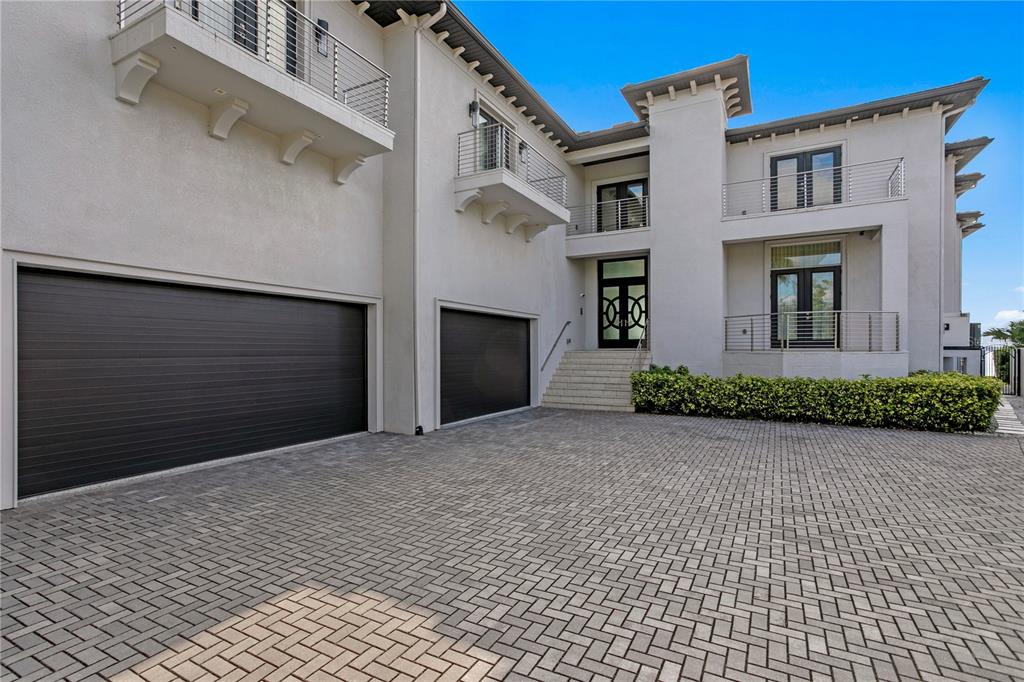 A modern white multi-story house features two dark garage doors and a paved driveway — 82 MARTINIQUE AVENUE, TAMPA, FL
