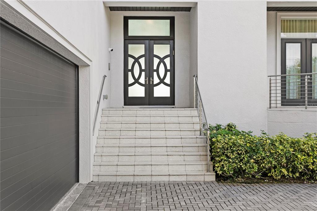 A set of concrete stairs leads to a modern double front door with horizontal glass panels — 82 MARTINIQUE AVENUE, TAMPA, FL