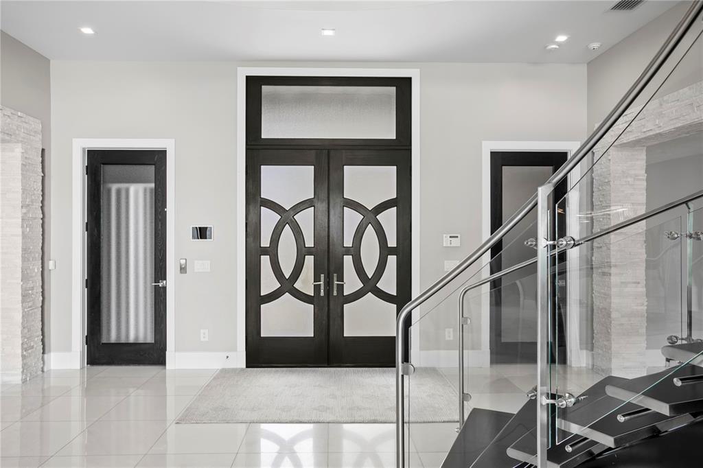 A grand foyer features a curved staircase, a black grand piano, and polished tile floors — 82 MARTINIQUE AVENUE, TAMPA, FL