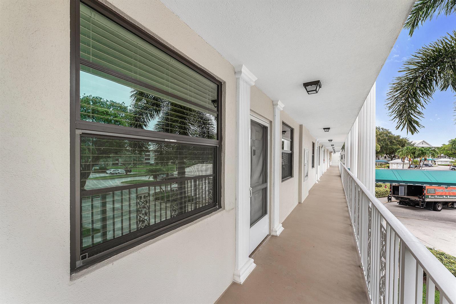 An outdoor walkway with white railings and columns runs along the side of a building — 6097 Balboa Circle # 202, Boca Raton FL 33433, BOCA RATON, FL